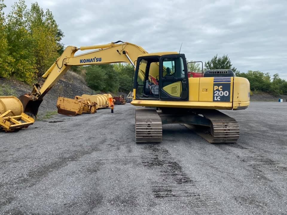Une excavatrice Komatsu jaune est garée sur un terrain en gravier.