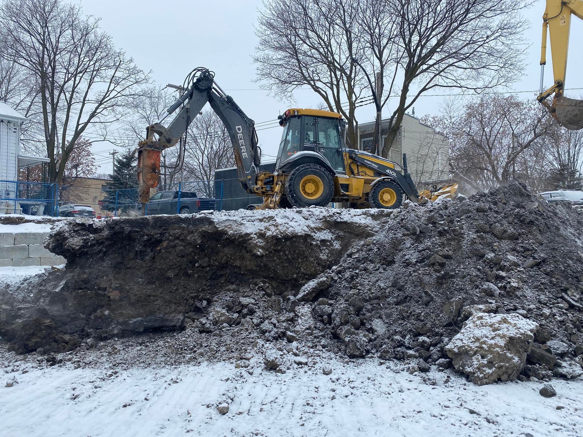 Une excavatrice jaune creuse un trou dans la neige.