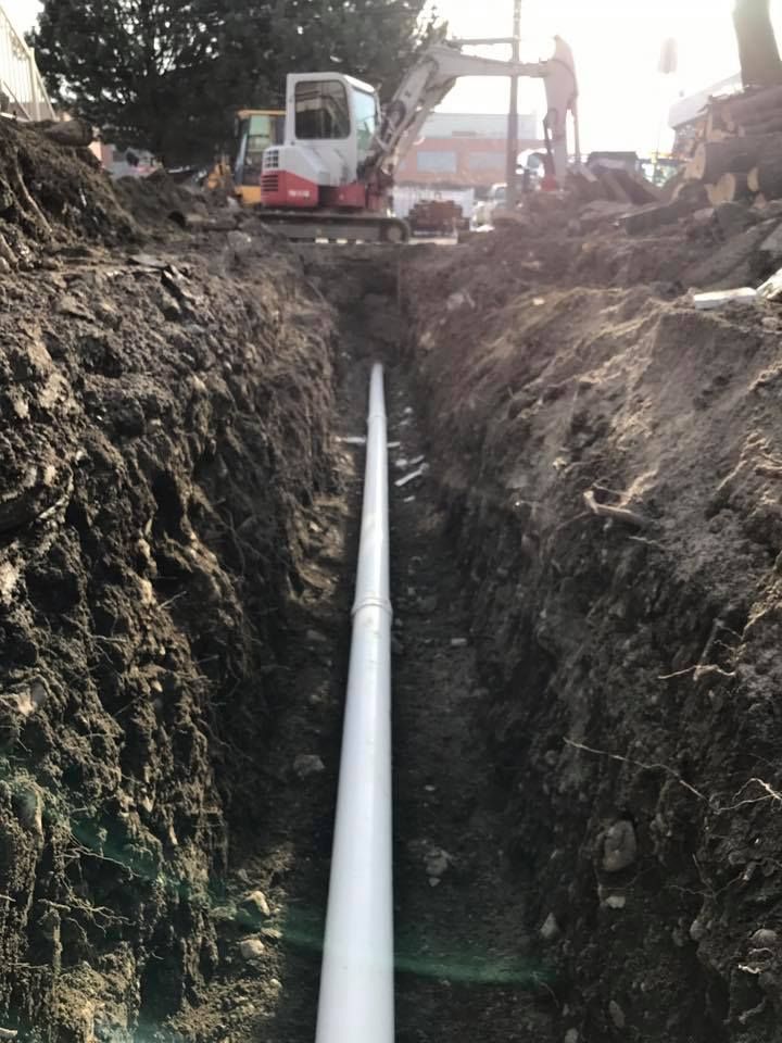 Un tuyau blanc est en train d'être installé dans un trou dans le sol.