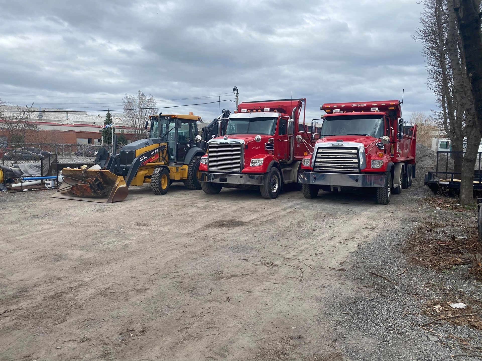 Une rangée de camions rouges est garée sur un terrain en terre.
