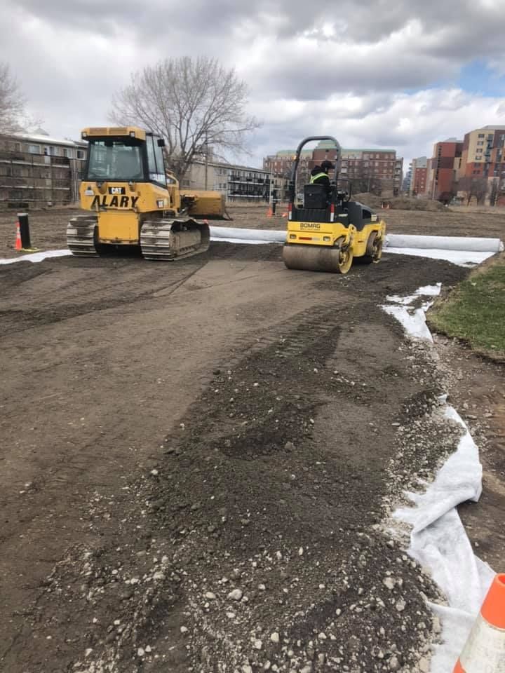 Un bulldozer et un rouleau compresseur travaillent sur un chemin de terre.