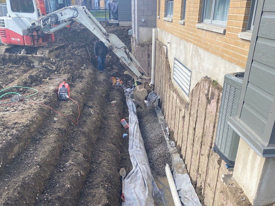 Une excavatrice creuse un trou devant un bâtiment.