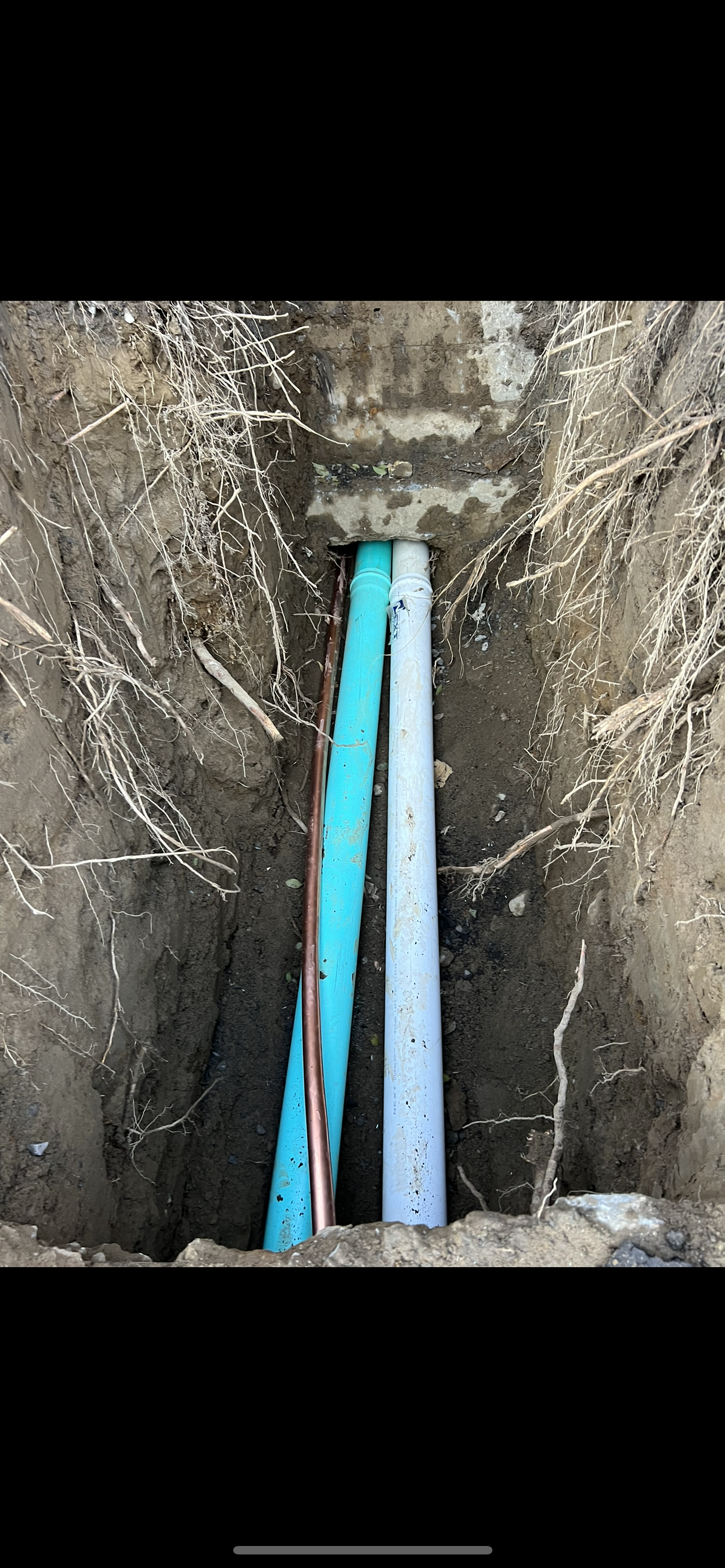 Un tuyau blanc est posé au milieu d'un trou dans le sol.
