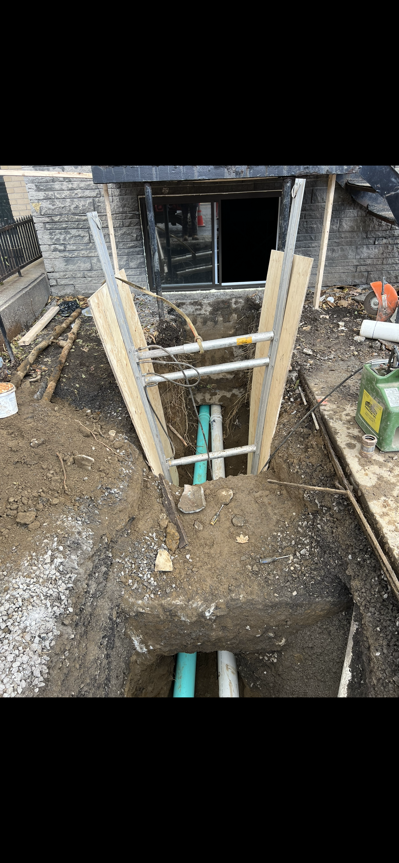 Une échelle est posée dans la terre à côté d'un trou dans le sol.