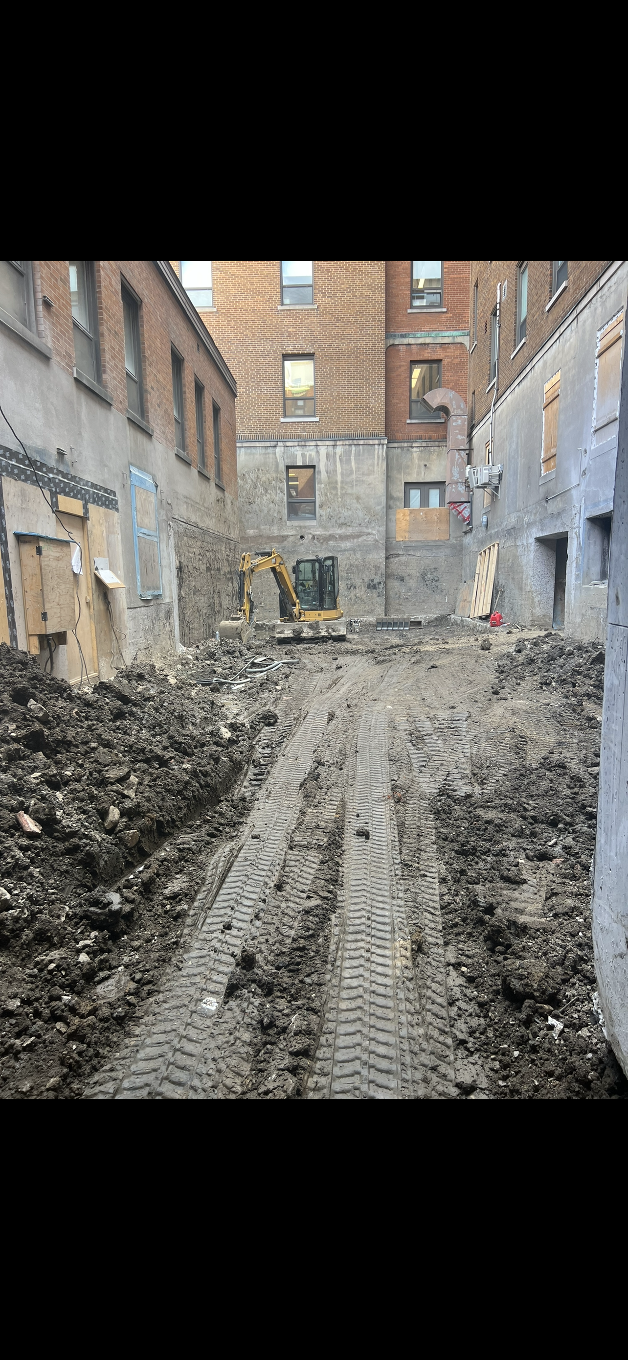 Un chantier avec beaucoup de terre et un bâtiment en arrière-plan.