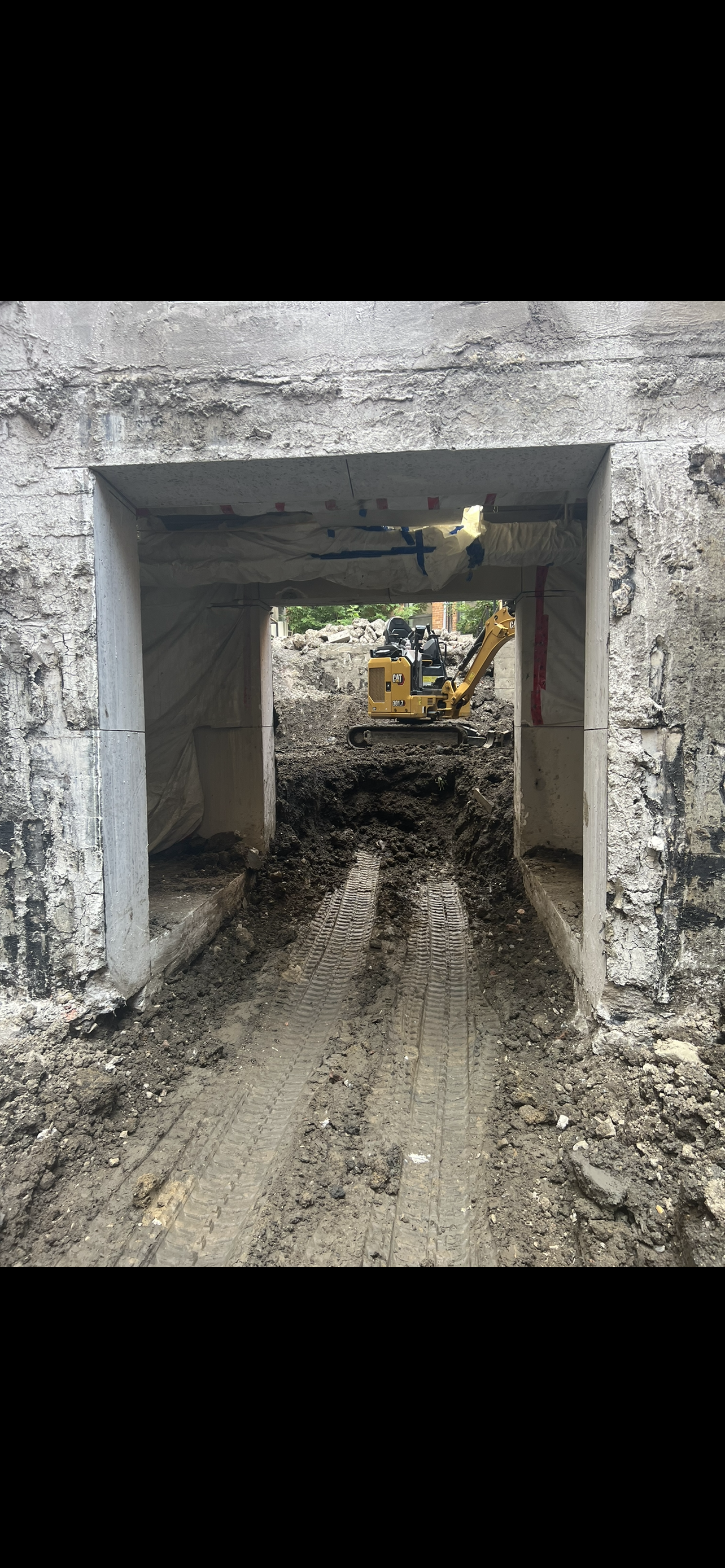 Une excavatrice jaune déplace de la terre sous un pont.