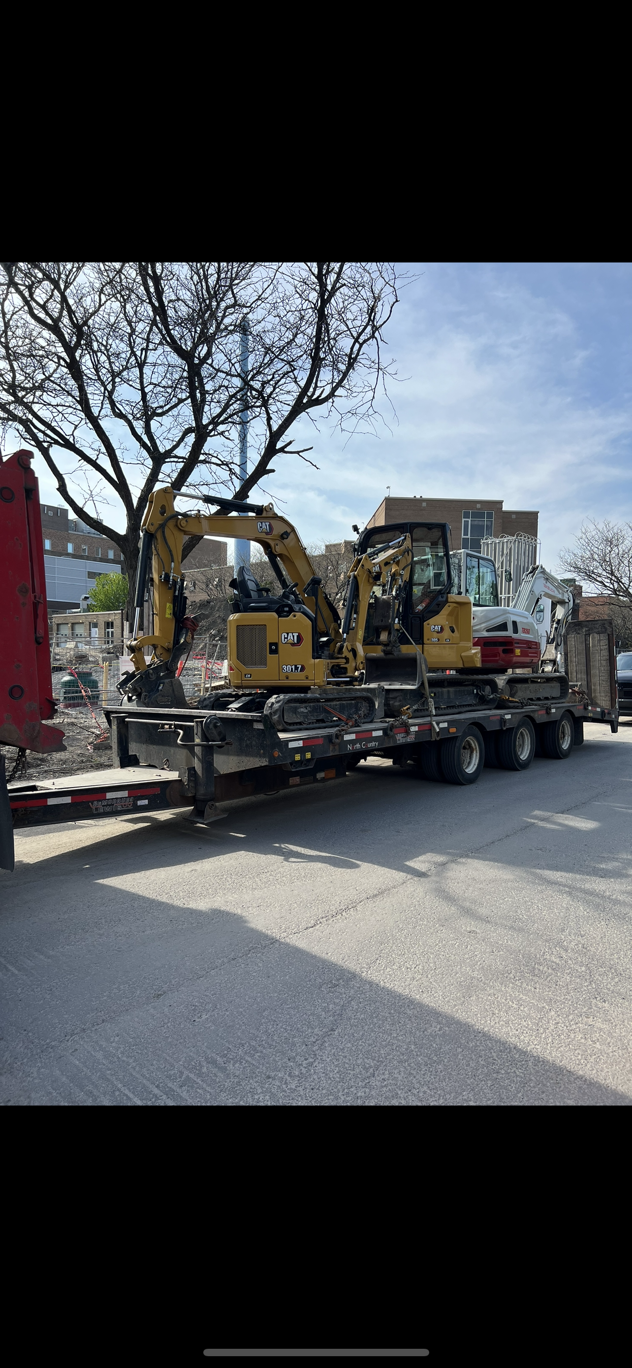 Un camion transporte deux excavatrices sur une remorque.