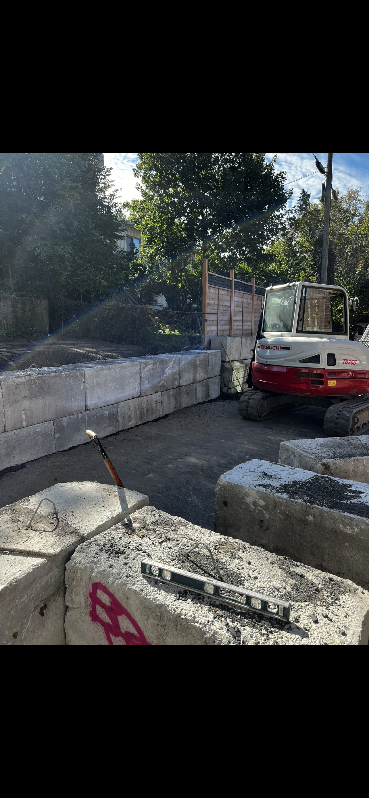 Une excavatrice rouge et blanche est assise sur un tas de blocs de béton.