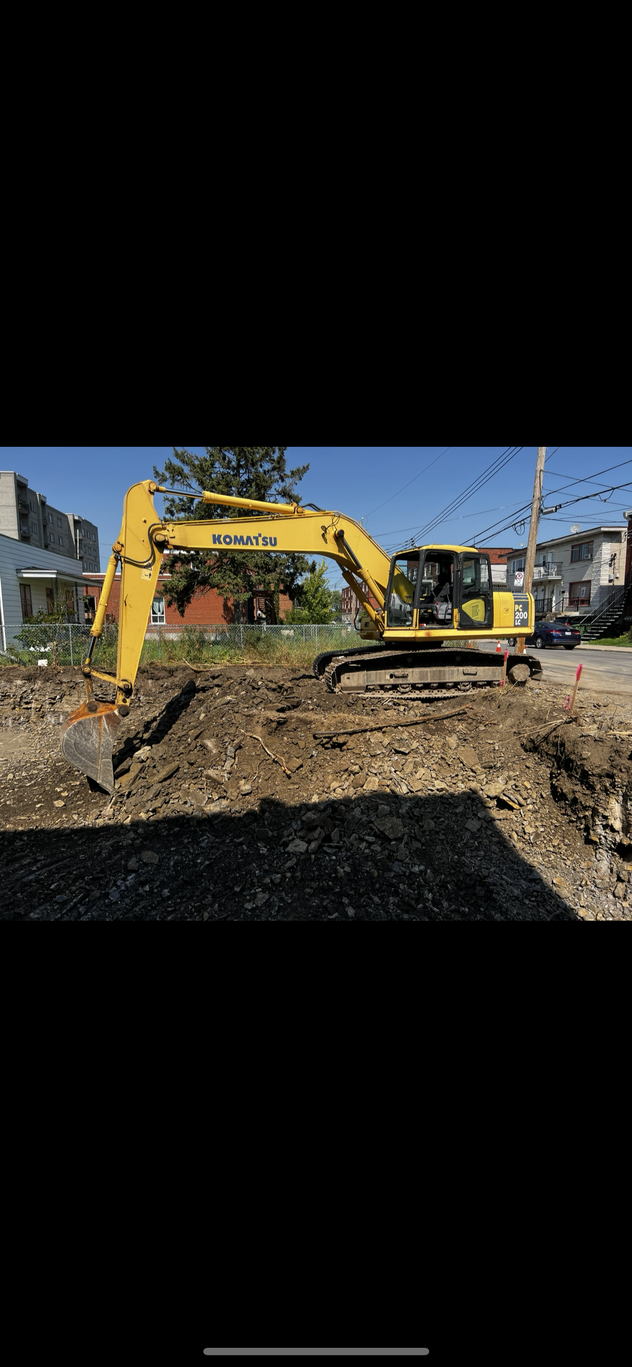 Une excavatrice jaune creuse un trou dans la terre.
