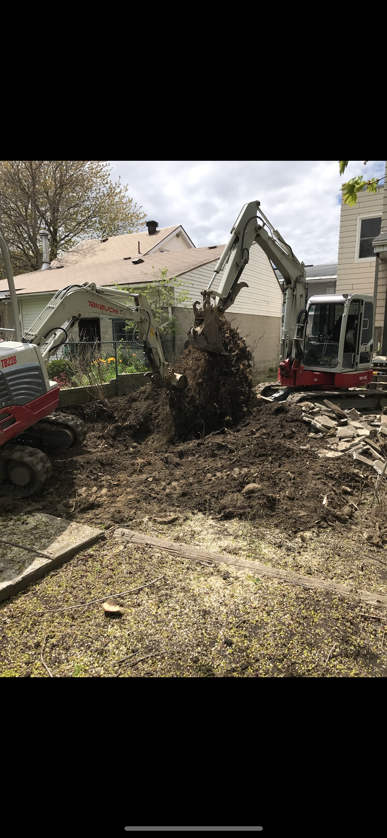 Un couple d'excavatrices creuse un trou dans une cour.
