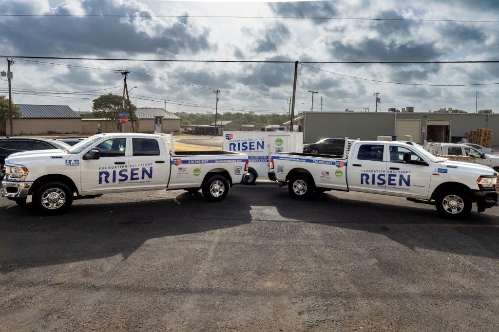 Two white trucks with the word risen on the side are parked in a parking lot.