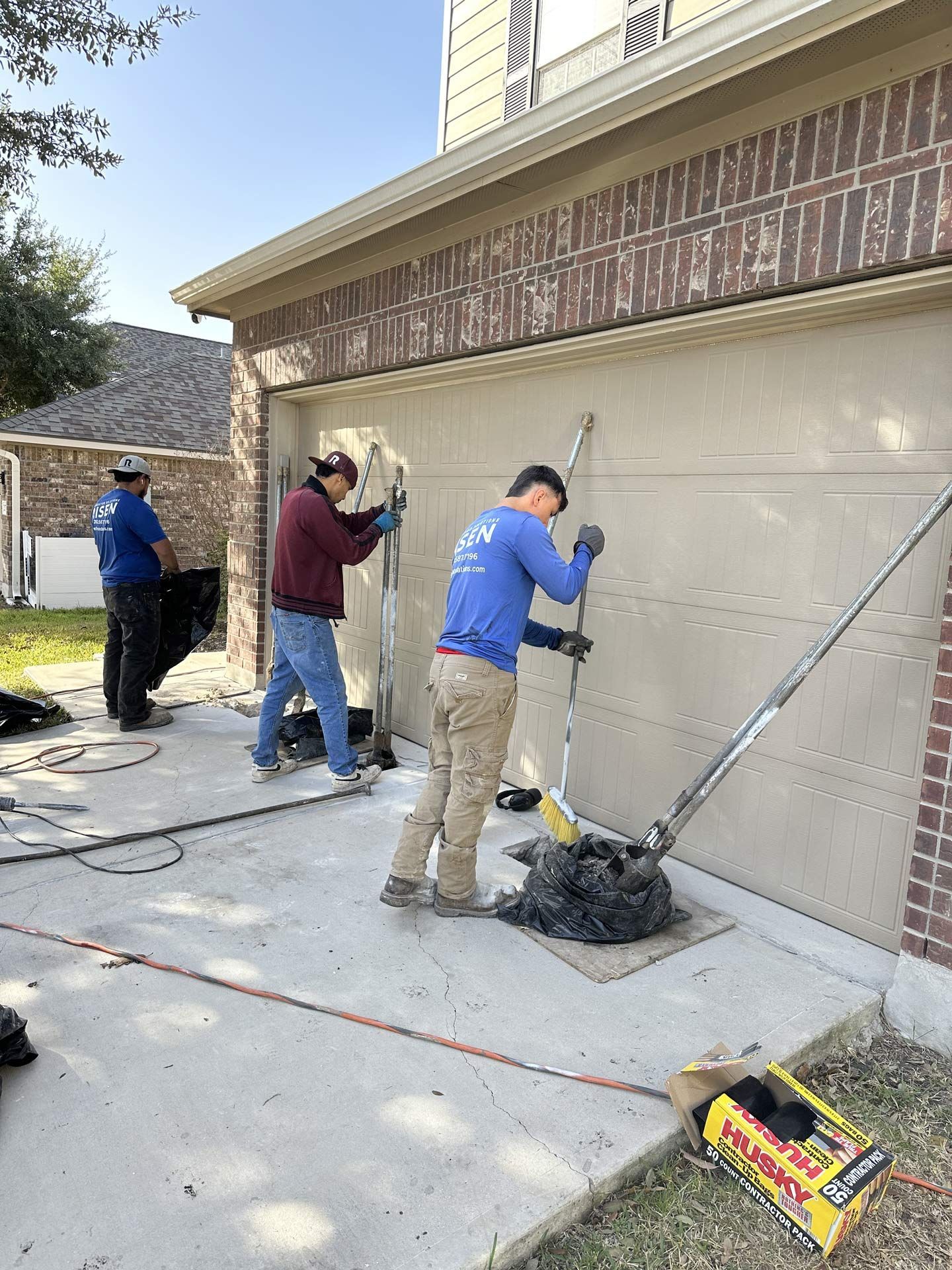 Three workers installing a garage door. Brick building, blue sky. Three workers installing a garage door. Brick building, blue sky.