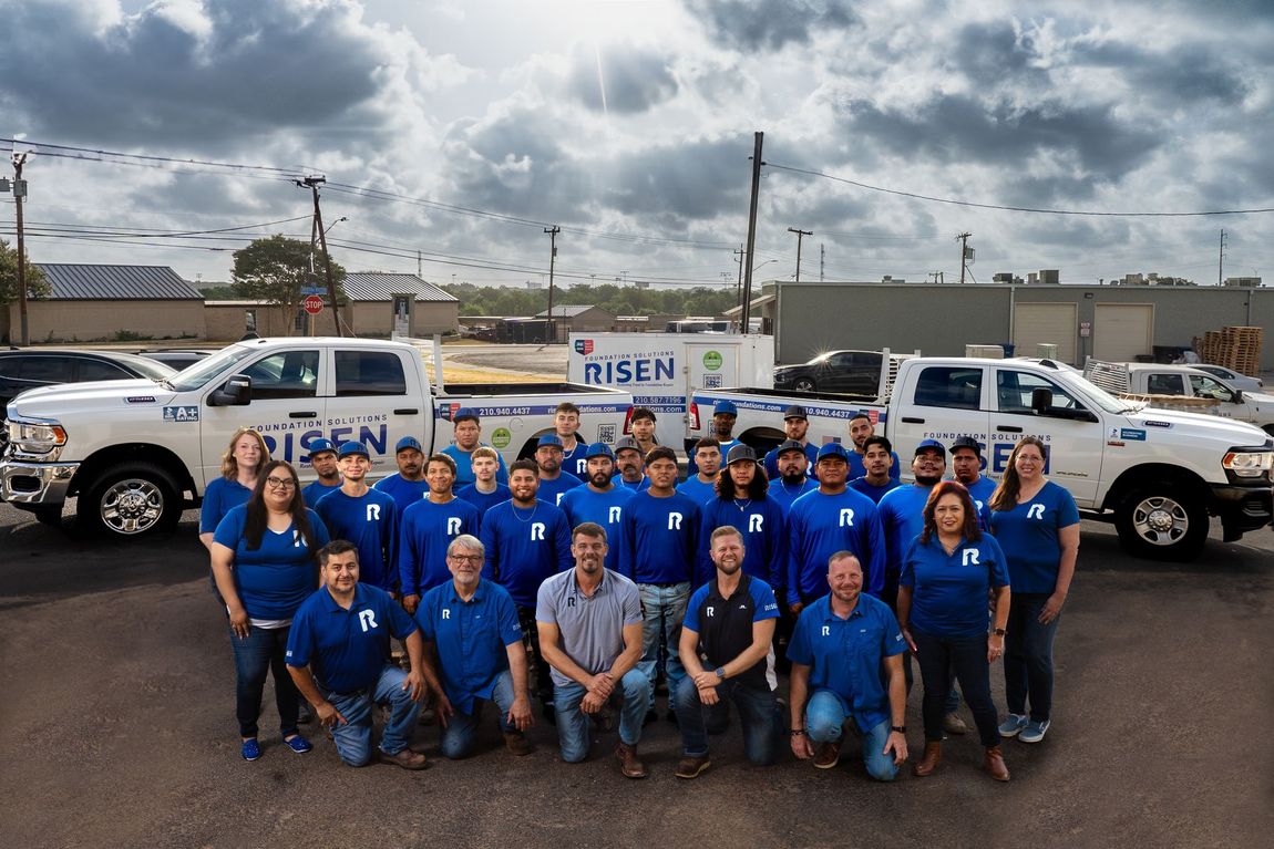 A large group of people are posing for a picture in front of trucks.