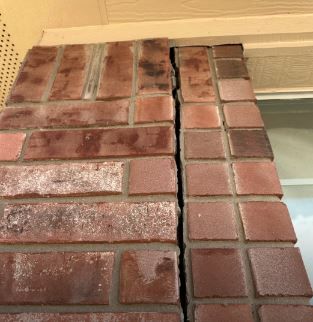 A textured brick wall displaying a prominent crack that disrupts its uniformity.