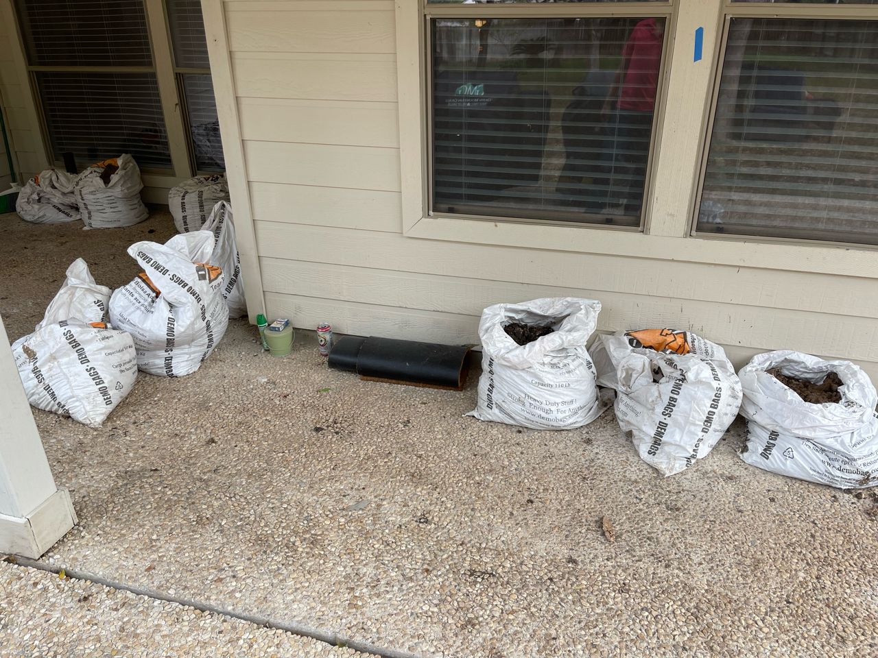 A bunch of bags are sitting on the ground in front of a house.