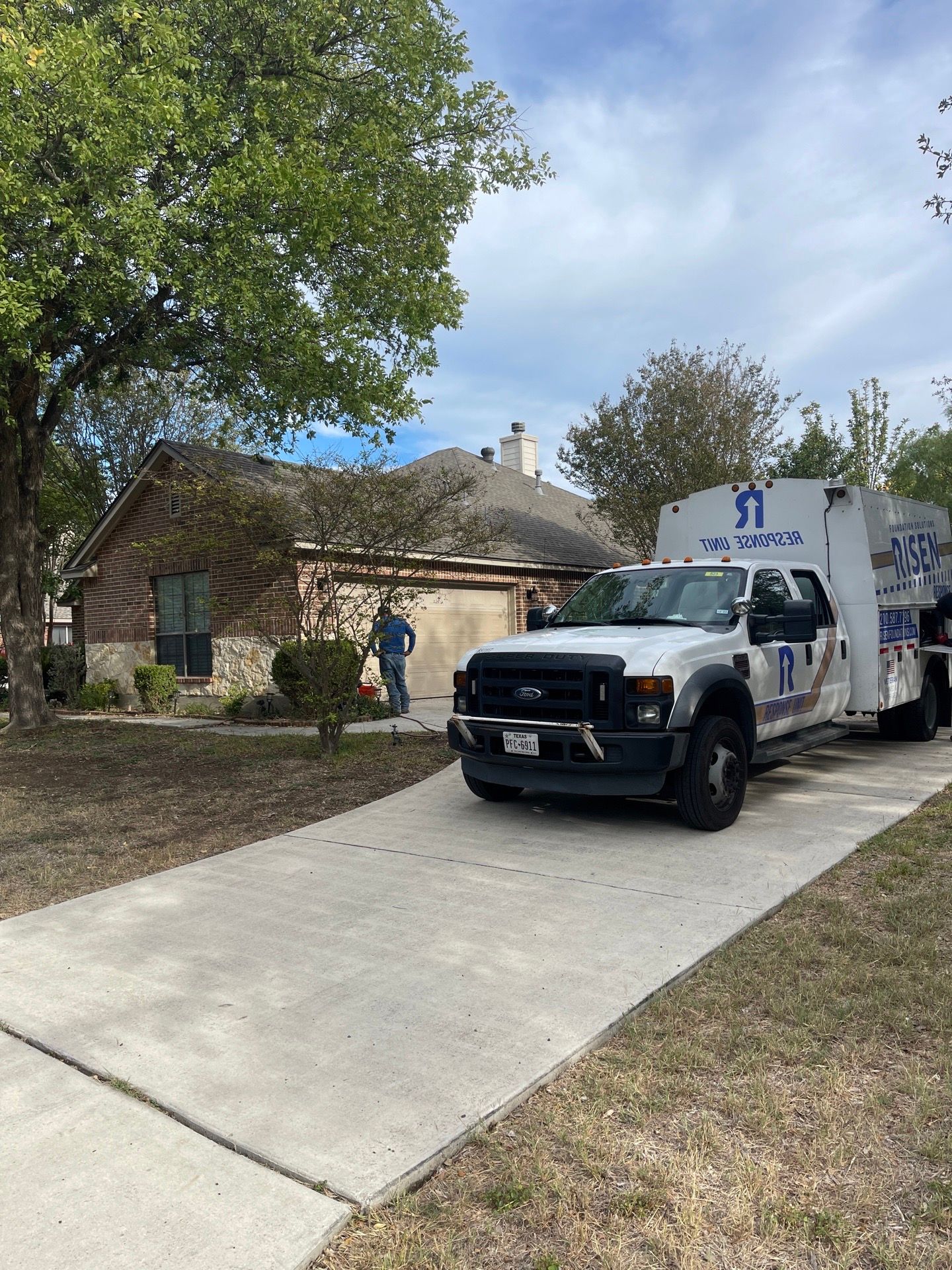 A white truck is parked in a driveway next to a house.