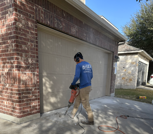 A man is working on a garage door with a hammer.