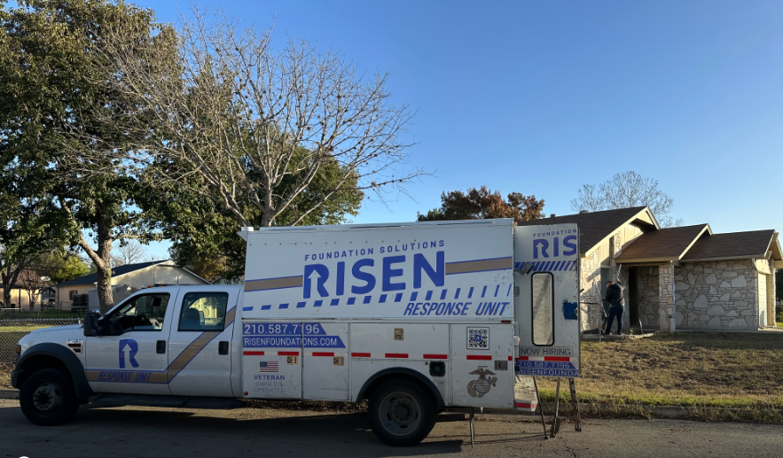 A white truck with the word risen on it is parked on the side of the road.