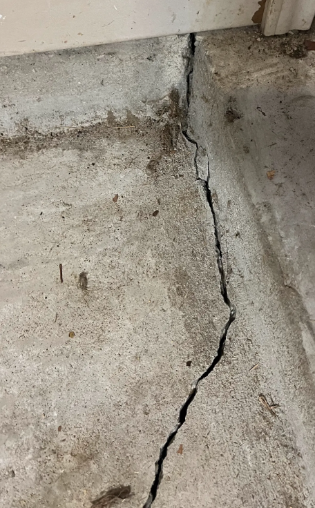 A visible crack in the concrete floor of a garage, highlighting wear and potential structural issues.