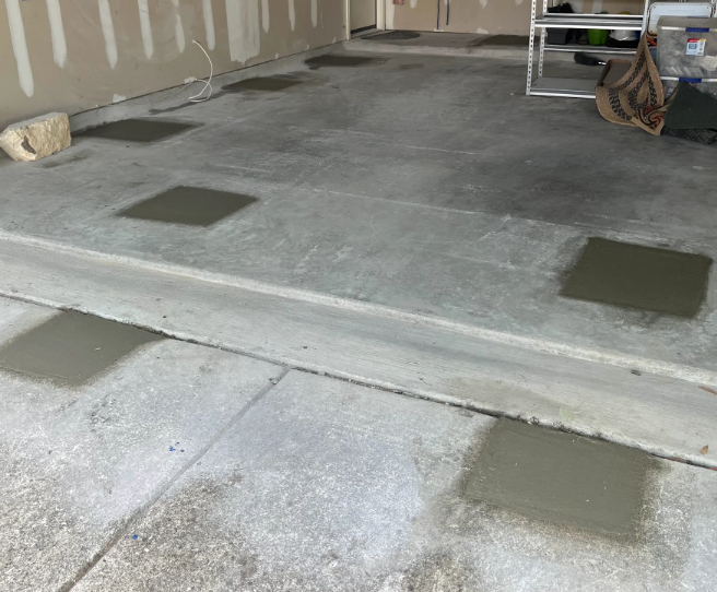A concrete floor is being repaired in a garage