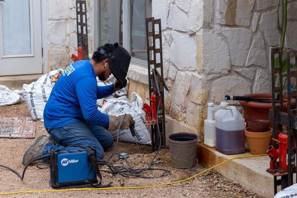 Worker welding, showcasing professional foundation repair for a building’s exterior structure. Worker welding, showcasing professional foundation repair for a building’s exterior structure.