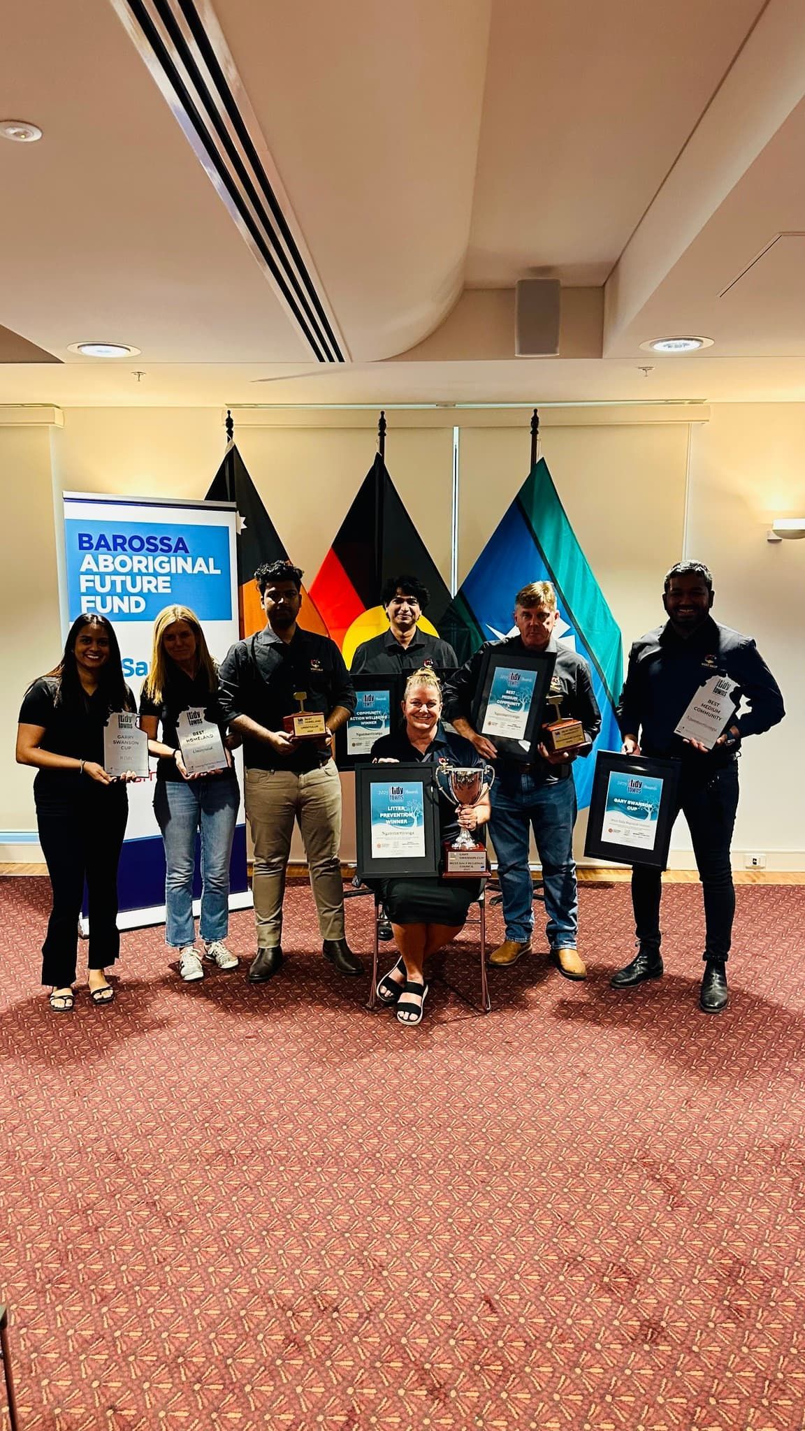 People marching and holding signs and flags. Many are wearing orange, under a blue sky.