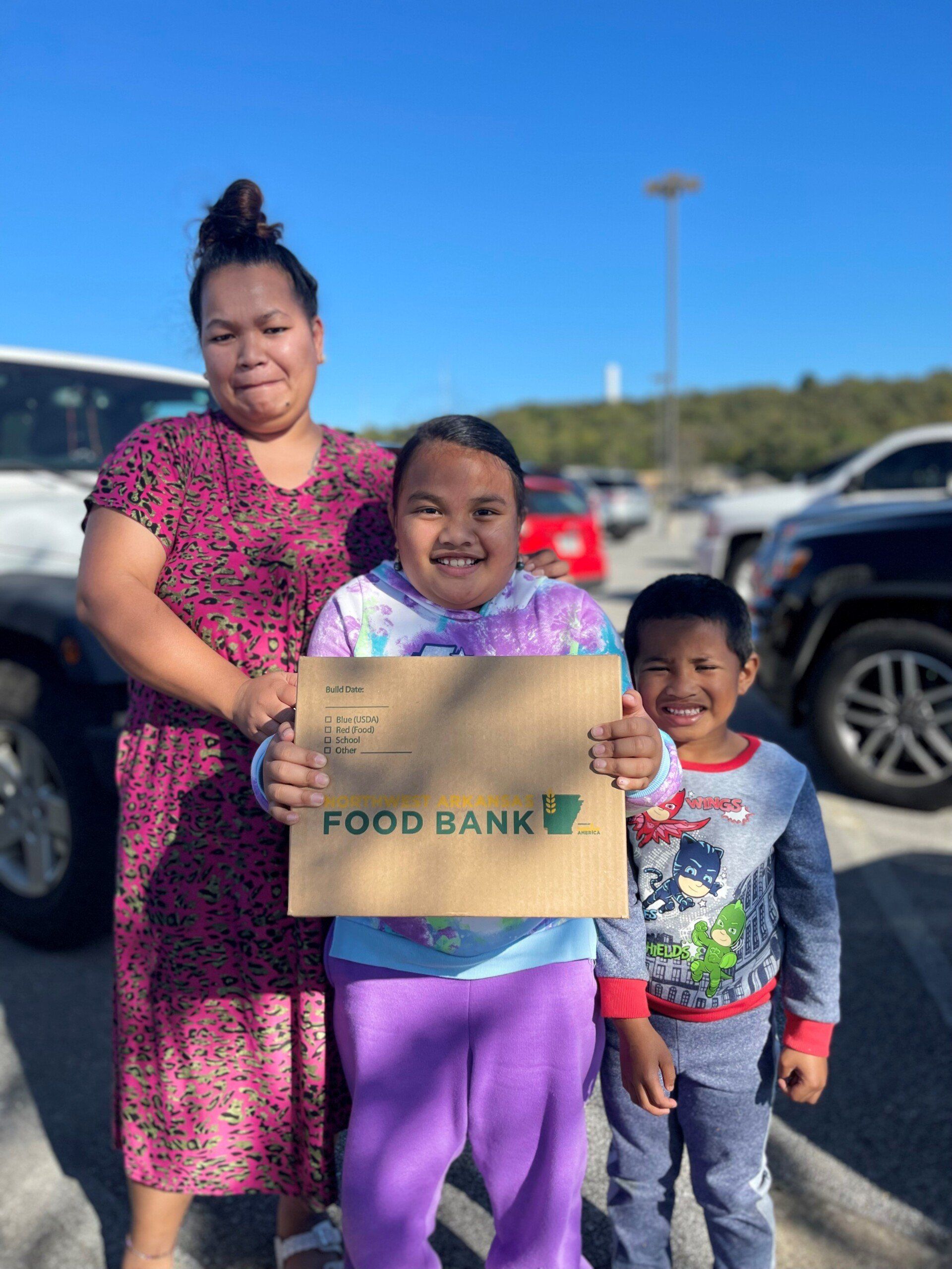 A woman and two children are holding a sign that says food bank.