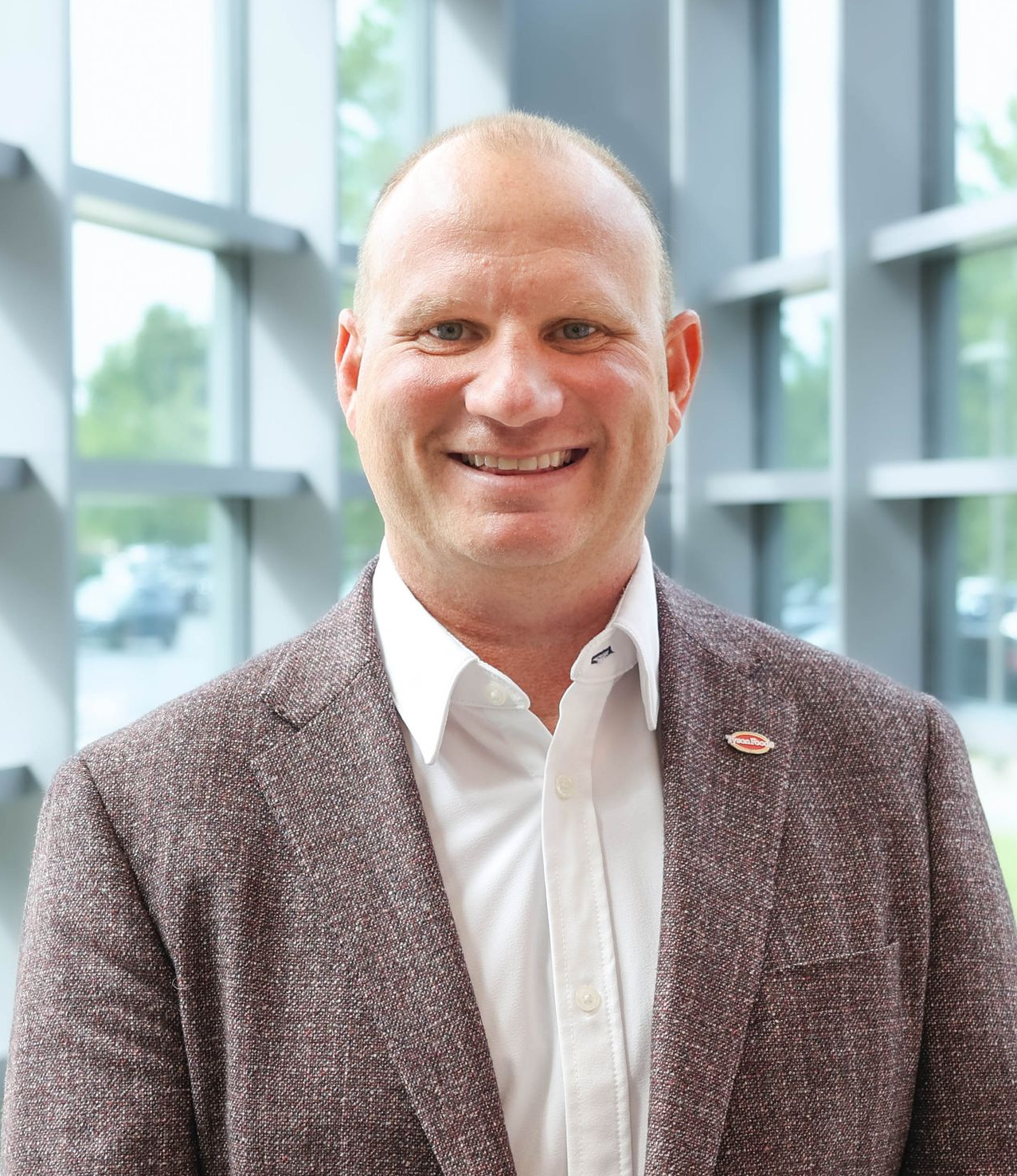A man in a suit and white shirt is smiling for the camera.