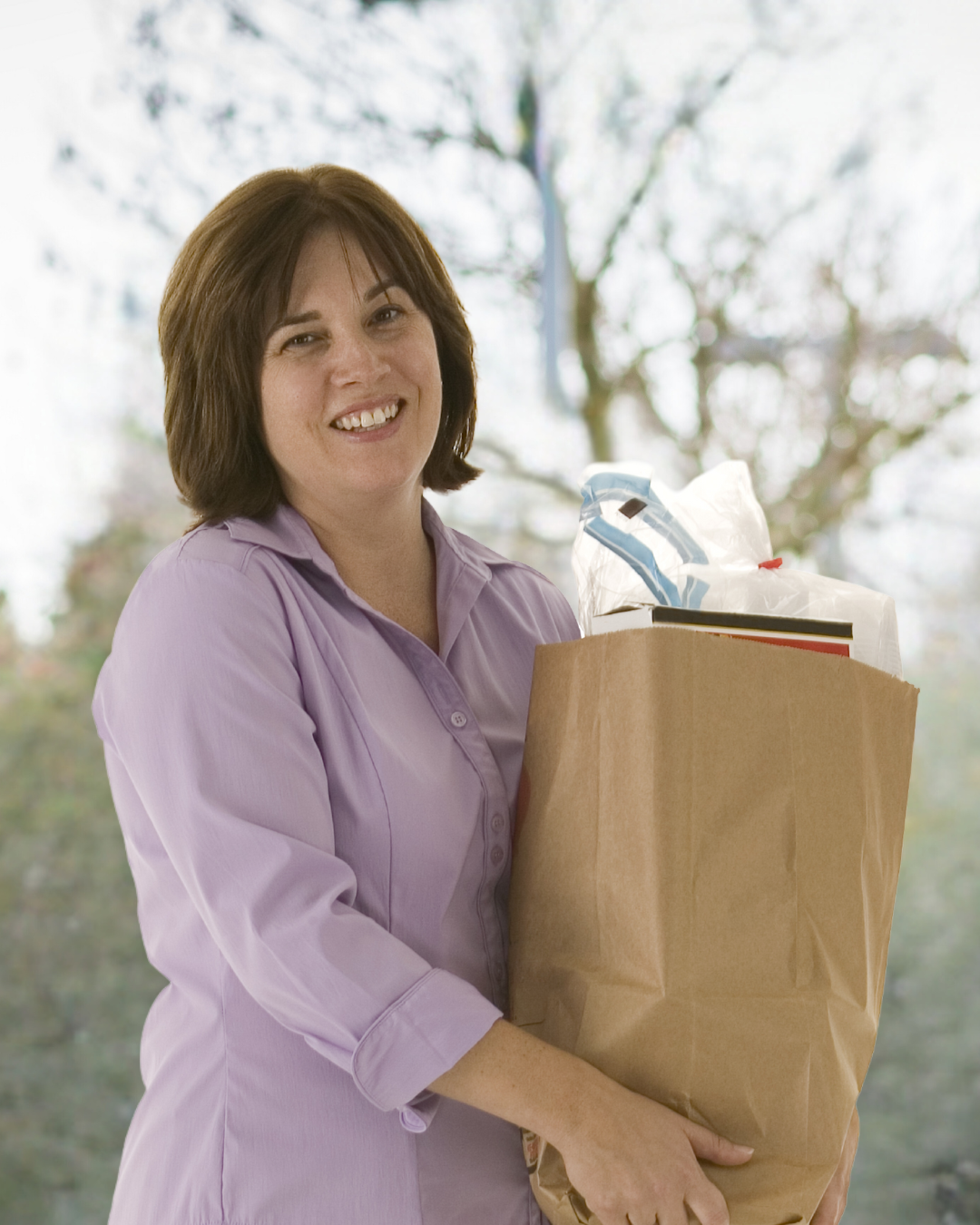 A woman in a purple shirt is holding a brown paper bag