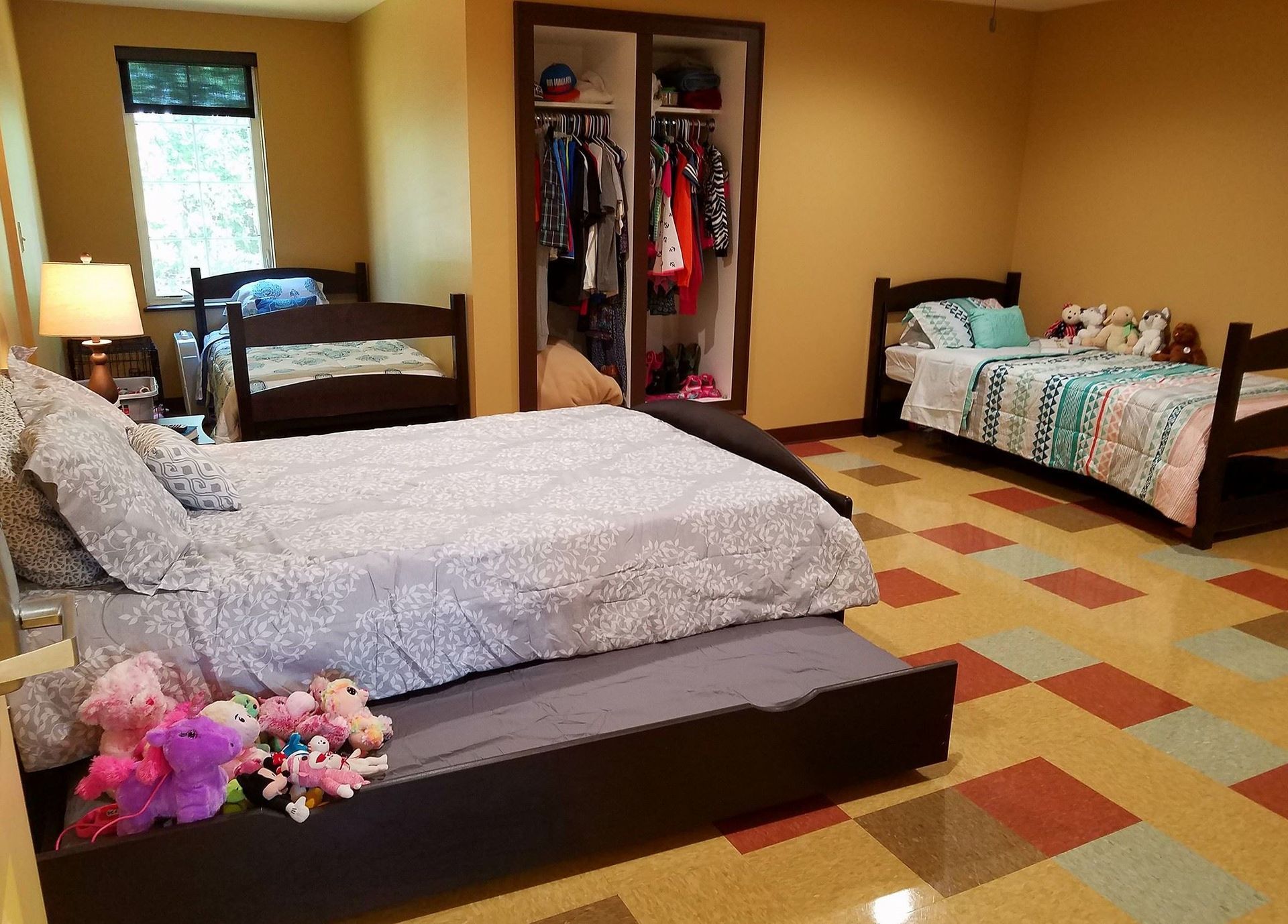 A bedroom with three beds and a closet.