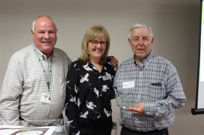 Three people are posing for a picture and one of them is holding an award