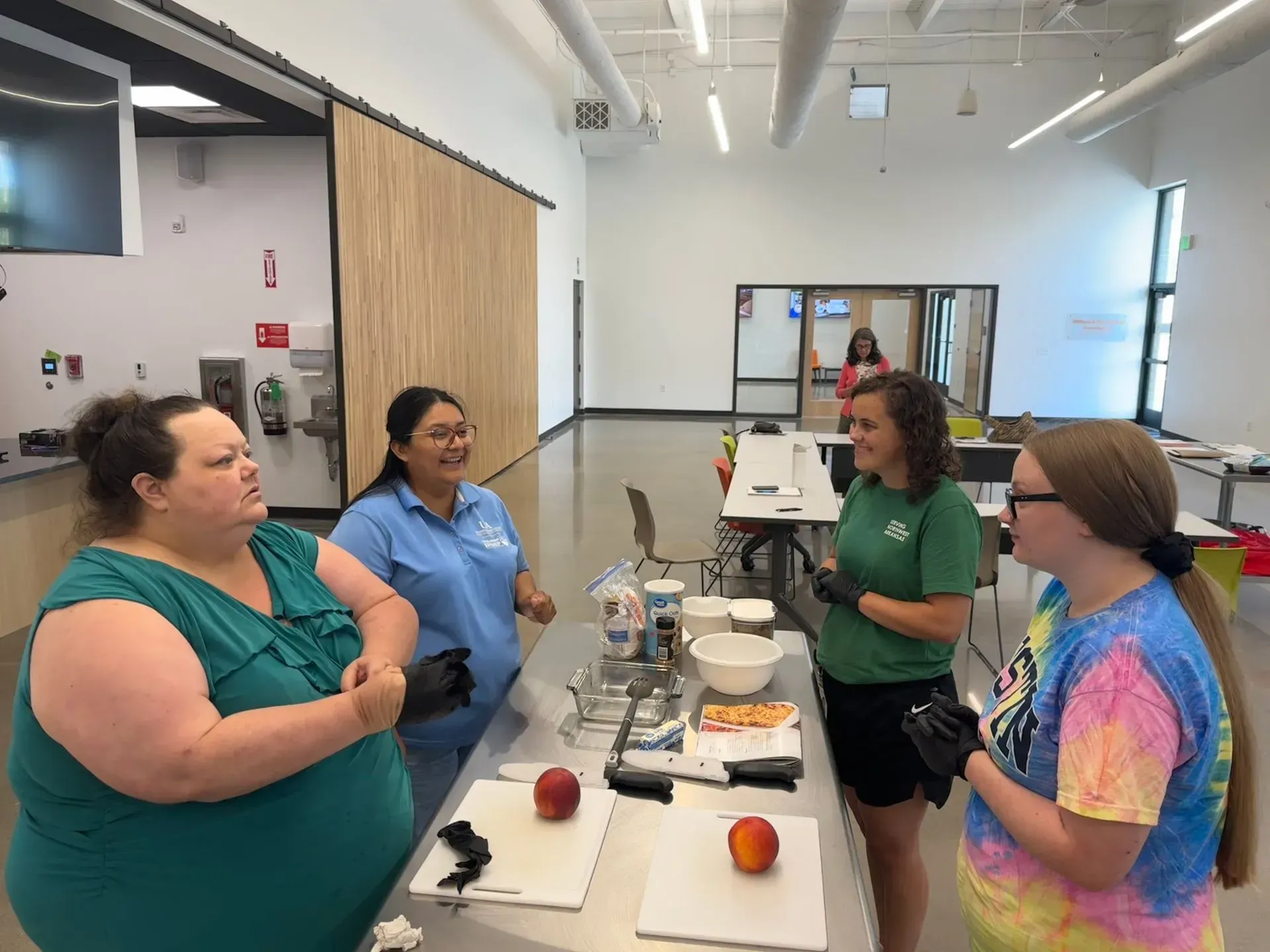 A group of women are standing around a table talking.