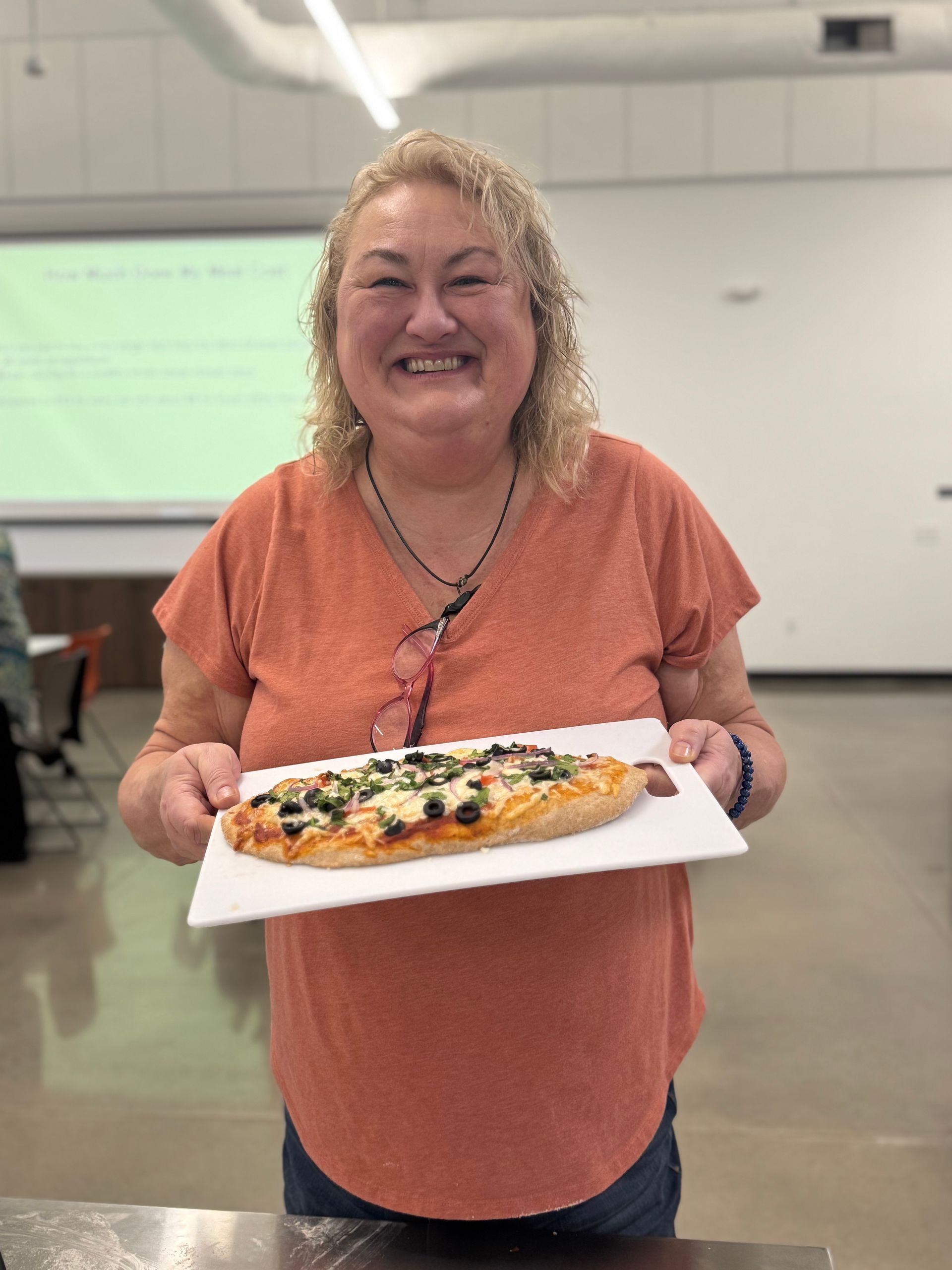 A woman is holding a white plate with a pizza on it