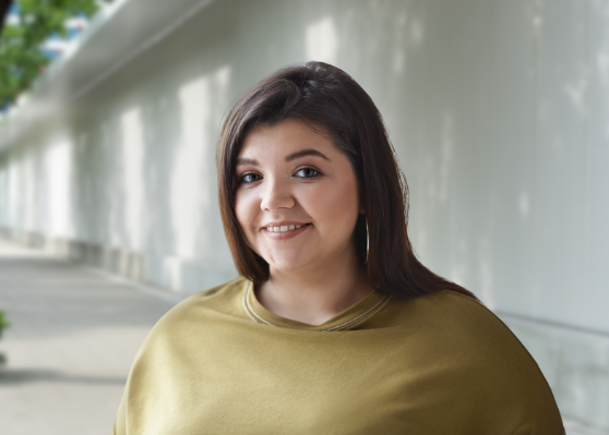 A woman in a green shirt is smiling for the camera.