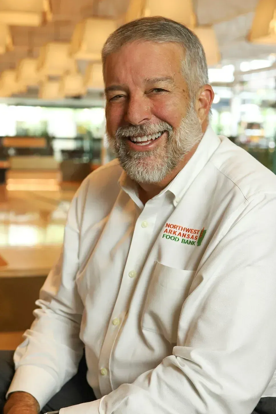 A man with a beard is smiling and wearing a white shirt