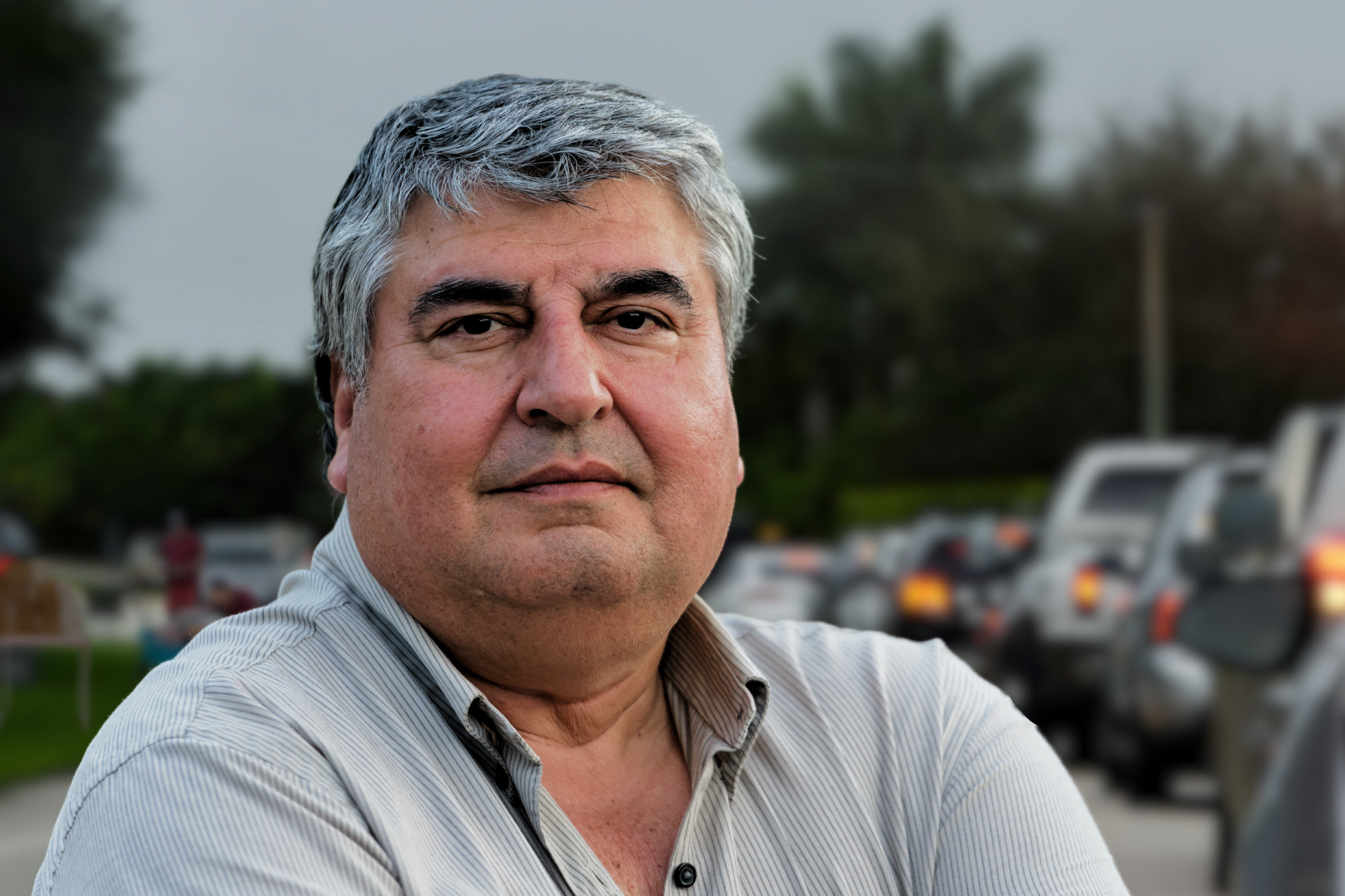 A man with gray hair is standing with his arms crossed and looking at the camera.