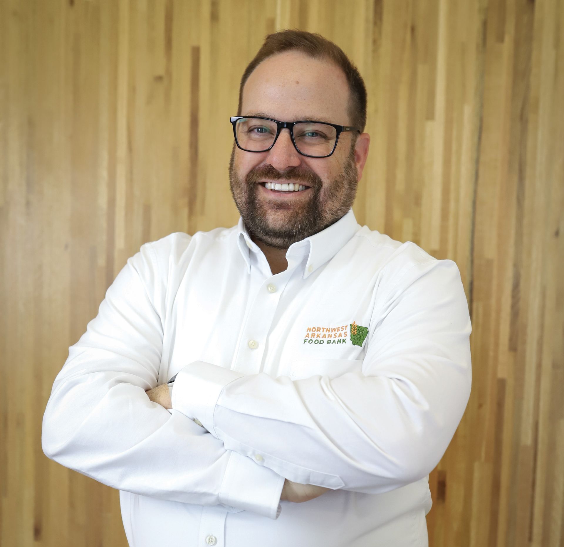 A man with a beard is smiling and wearing a white shirt
