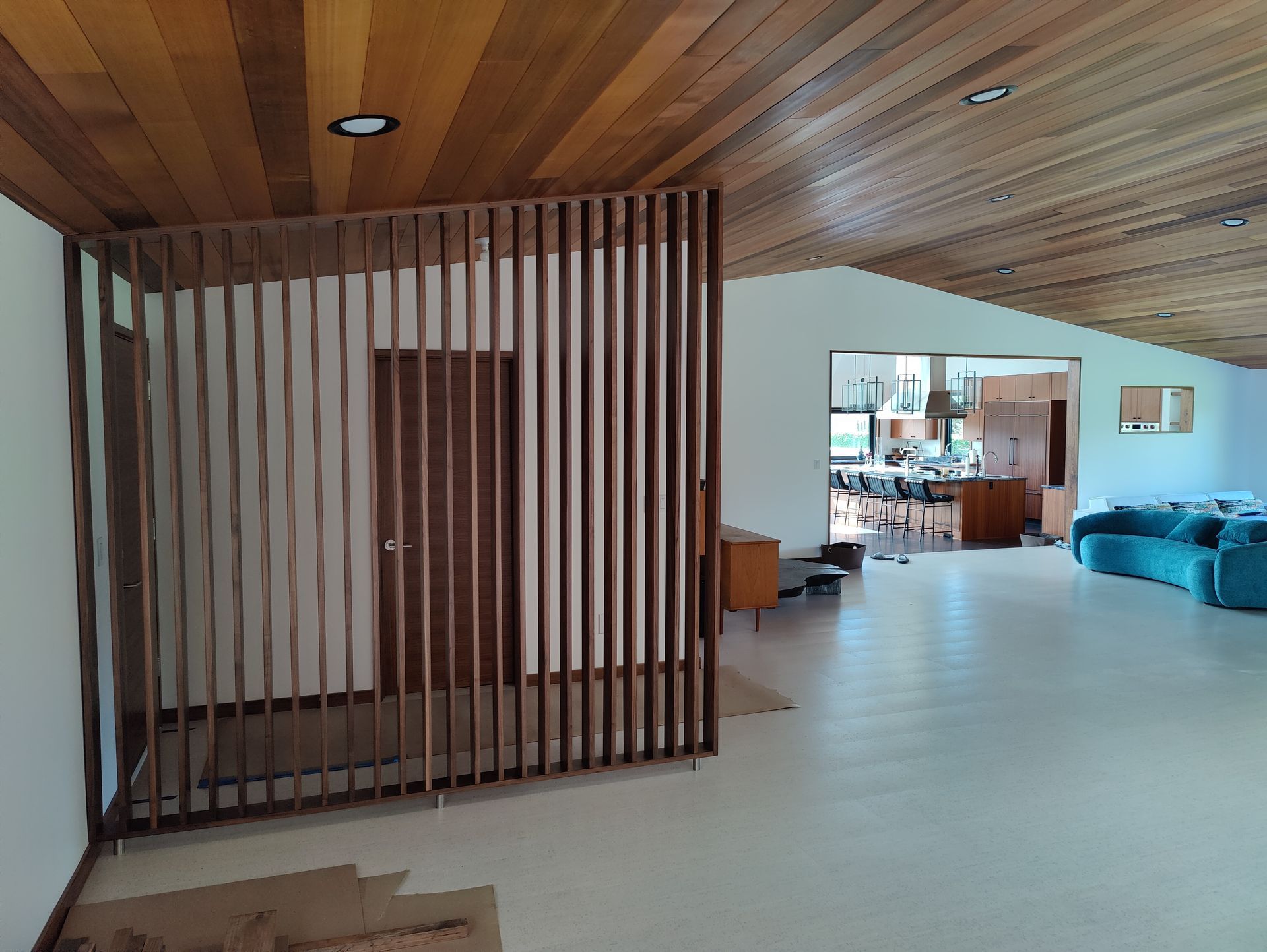 Wooden bench with open cubbies and a drawer under windows, plants in view