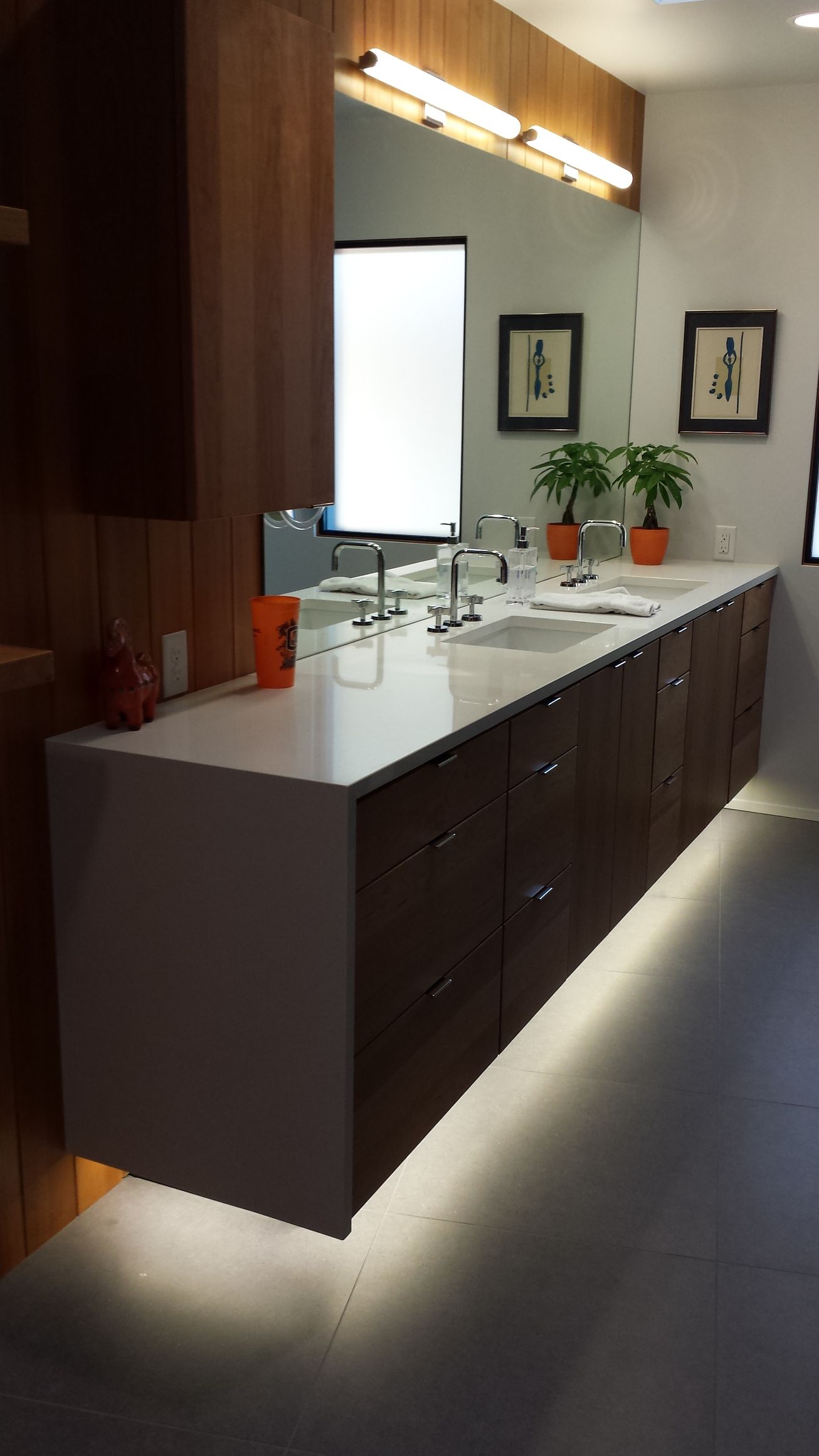Modern bathroom with a wall-mounted wooden vanity and large mirrors