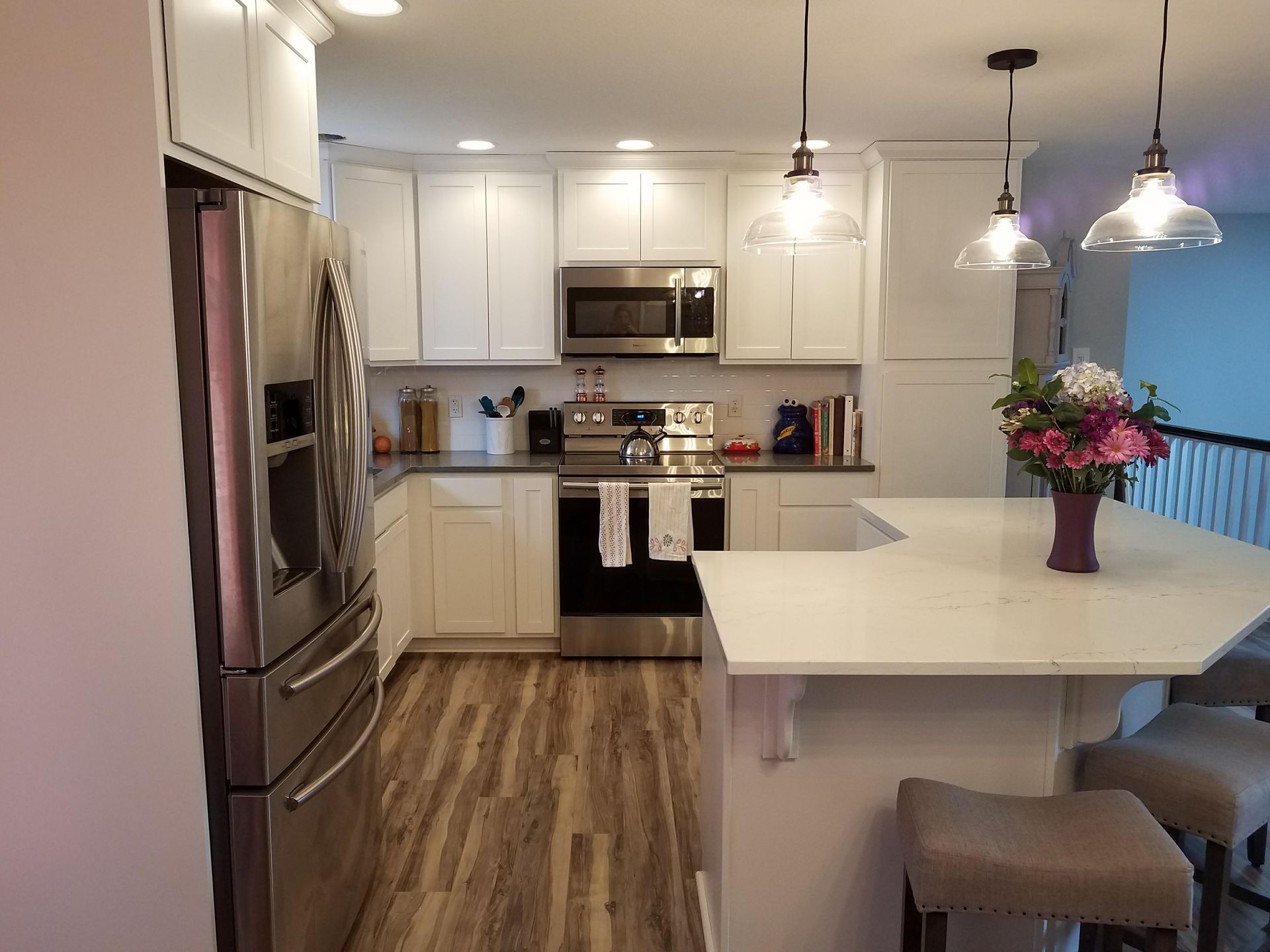 White and black kitchen with island, range hood, pots, and various utensils