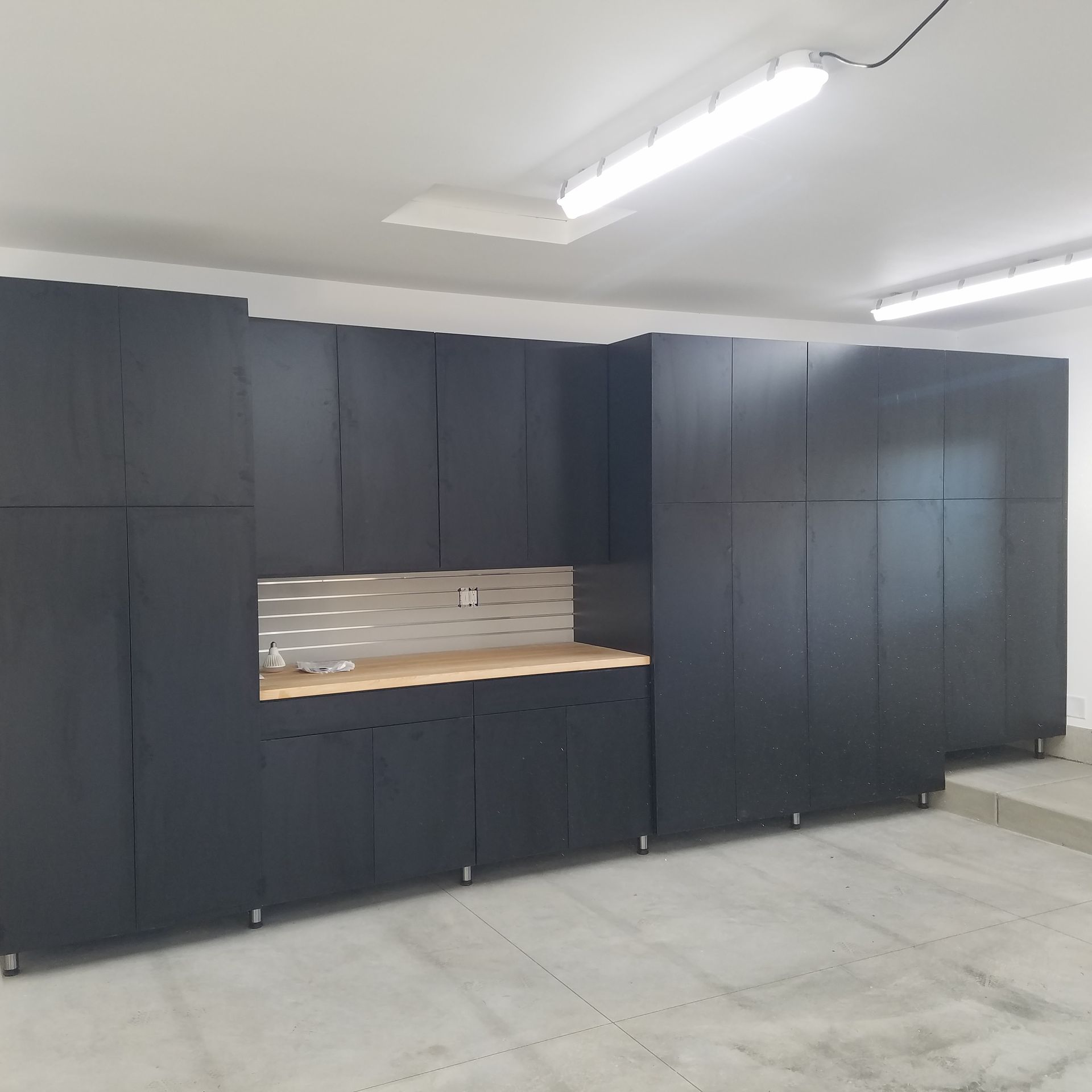 Garage interior with tools, workbench, cabinets, door, and vacuum cleaner