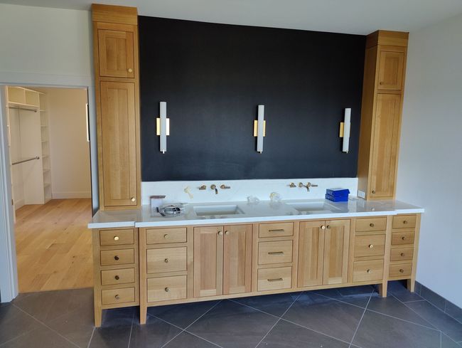 Two people measuring and marking wood on a workbench