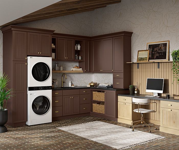 A laundry room with brown cabinets, a stacked washer/dryer, a desk, and a light-colored rug. A laundry room with brown cabinets, a stacked washer/dryer, a desk, and a light-colored rug.