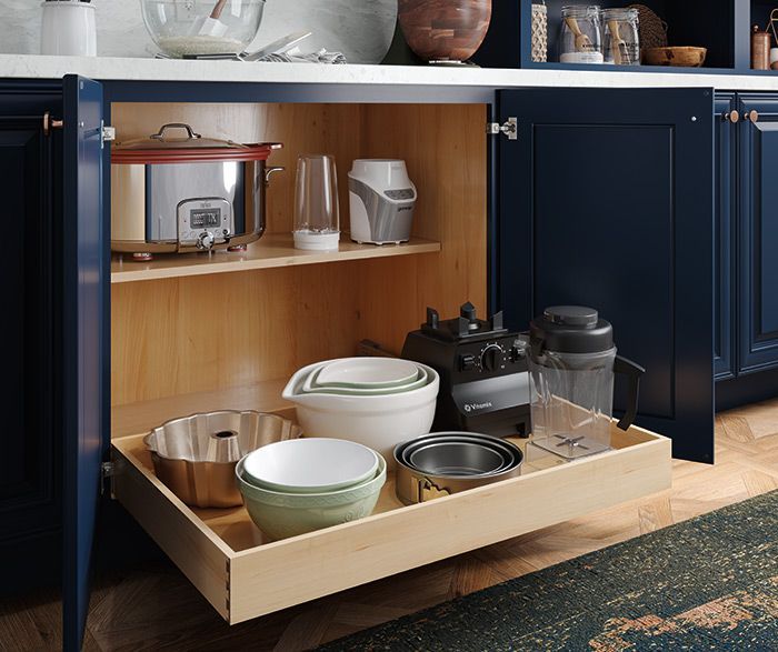 Navy kitchen cabinet open, pull-out shelf with bowls and blenders. Upper shelf: slow cooker, blender. Navy kitchen cabinet open, pull-out shelf with bowls and blenders. Upper shelf: slow cooker, blender.