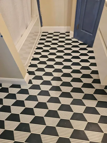 Black and white geometric patterned floor in a hallway with a blue door and a staircase.