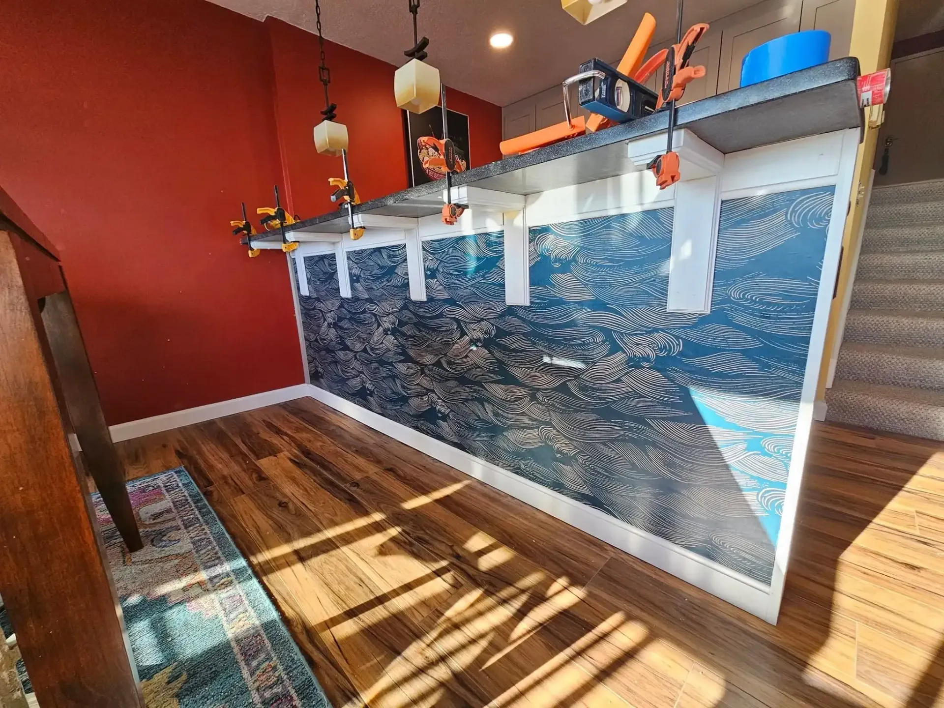 Blue patterned wall with white trim, wood floor, red wall, and lights.