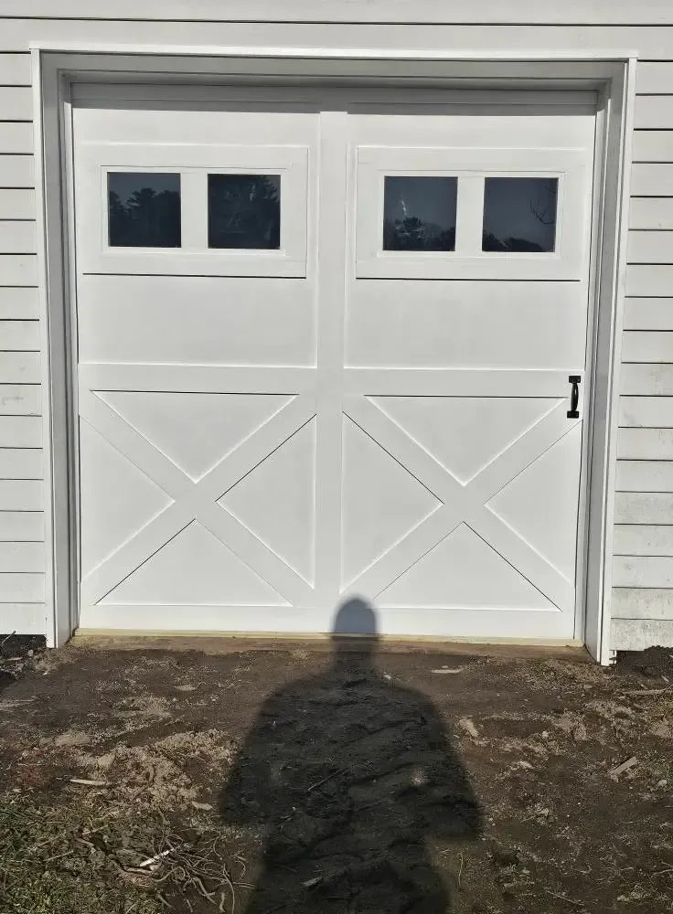 White garage door with windows, cross braces, and a shadow in front.