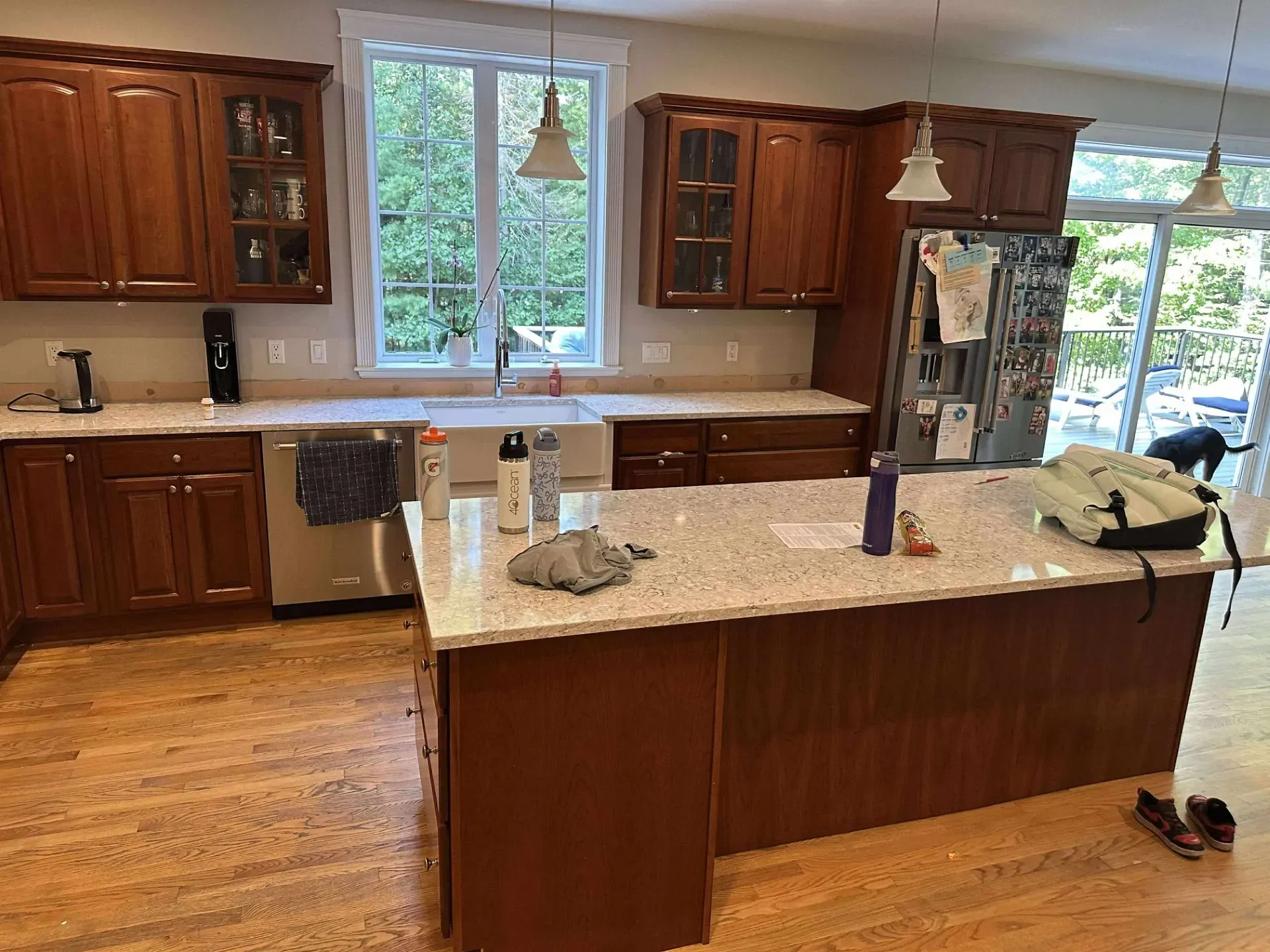 A kitchen with wooden cabinets, light-colored countertops, a large island, stainless steel appliances, and wood floors.