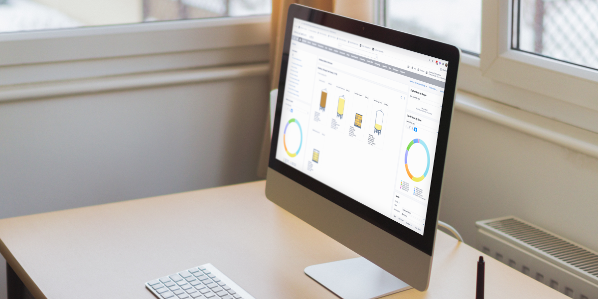 Desktop computer with distillery software dashboard showing tanks and financial data