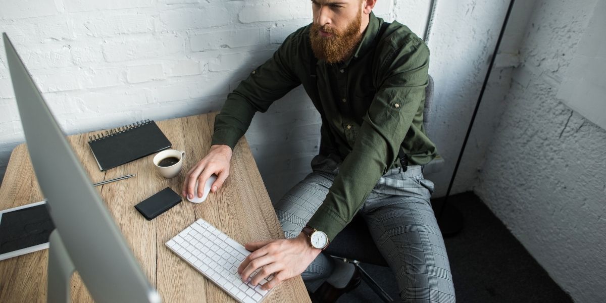 A man is sitting at a desk using a computer.